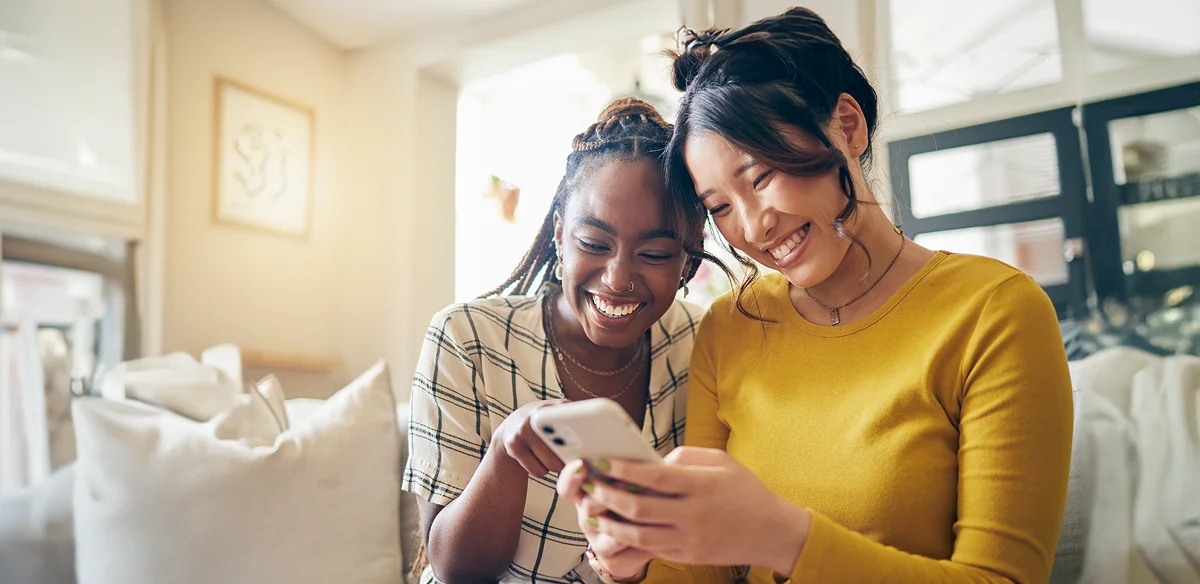 Two students smiling while looking at their phone
